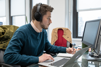 An On-Ramper writes on a giant sticky note while a second On-Ramper looks on.