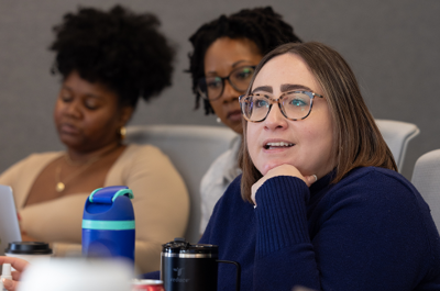 Three members of the On-Ramps team sit at a conference table smiling and laughing.