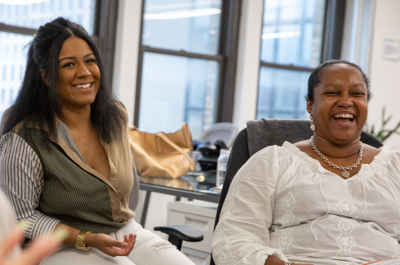 Two people sit in the On-Ramps office, laughing and smiling. 