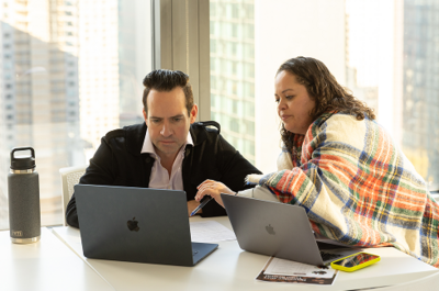 On-Rampers sit around a conference table with a Zoom presentation in the background. One On-Ramper is mid sentence with others listening intently.